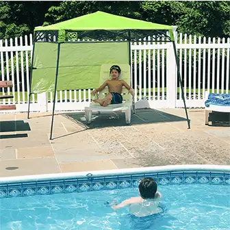 a child under a pop-up canopy that's next to a swimming pool