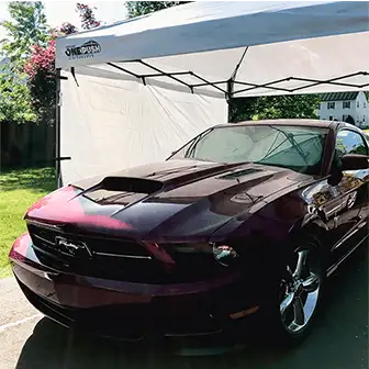 a Ford Mustang parked underneath a pop-up canopy
